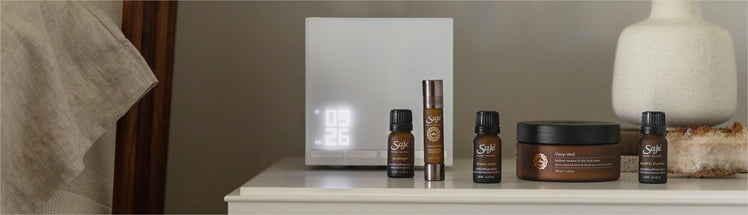 Saje diffuser, Tranquility Roll-on, Sleep Well Body Butter, and diffuser blends on a nightstand
