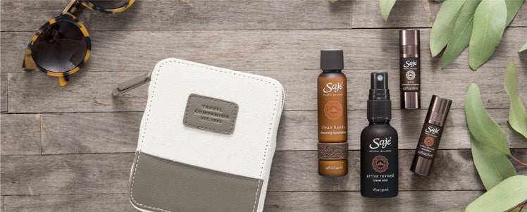 Saje travel kit placed with greenery and sunglasses