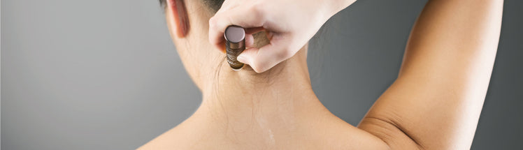 A person applying pain relief onto back of their neck 