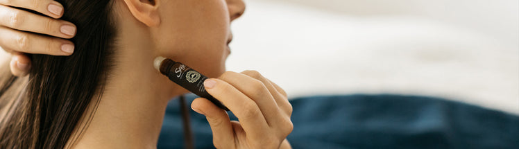 A person applying sleep well roll on onto their neck