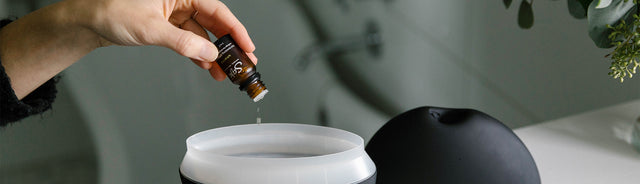 A person dropping essential oils into Aroma Om Deluxe diffuser 