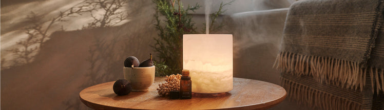 Unwind diffuser blend place on table with Saje diffuser and fruit bowl