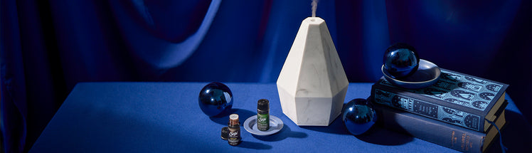 Saje diffuser placed with diffuser blends on blue table