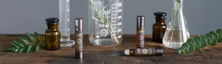 Saje Peppermint Halo, Pain Release, and Stress Release Roll-ons with plants in the background