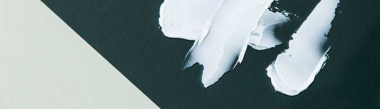 Saje essential oil lotion artfully smeared on a rich green background