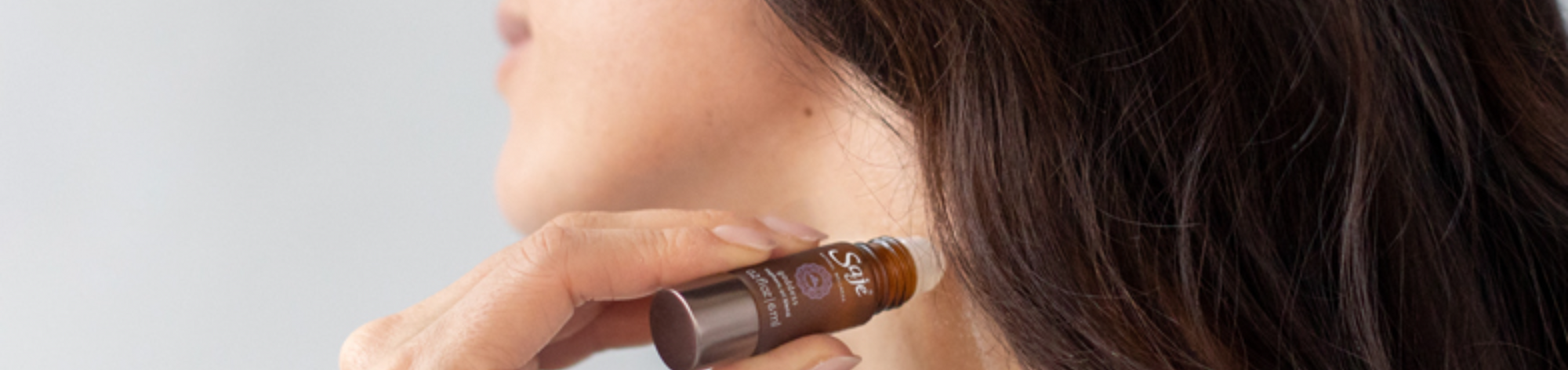 Woman applying 100% natural Saje Remedy roll on