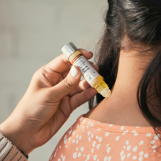 Adult rolling Sunny Mood roll-on on back of child's neck