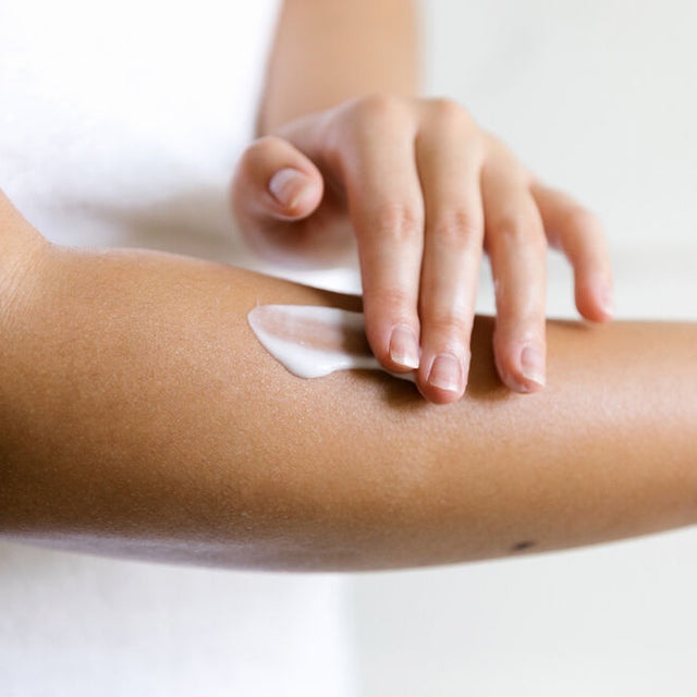 A hand applying lotion to the opposite forearm