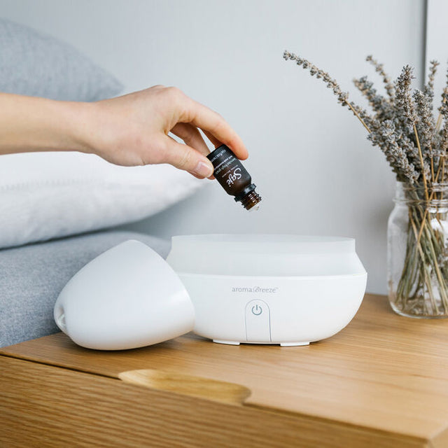 person dropping Lavender 100% pure grade essential oil into diffuser