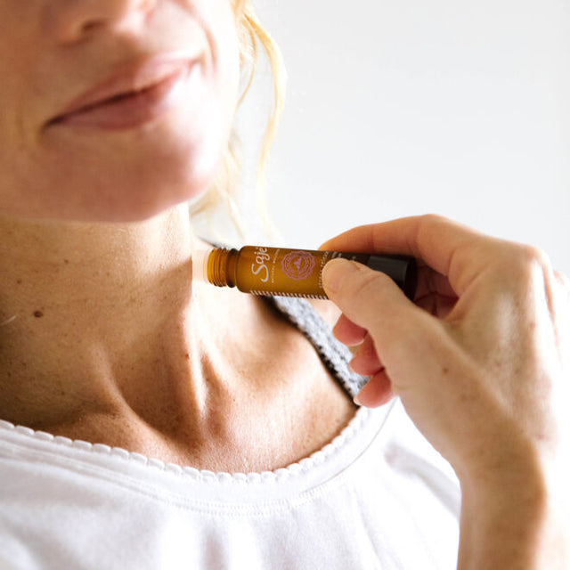 A woman applying Stress Release soothing oil blend to her necka