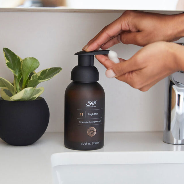 Hands dispensing Tingle Mint foaming hand soap from the bottle, next to a sink