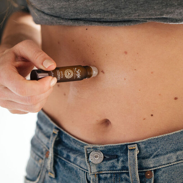 A women applying Gutzy soothing belly blend roll-on 0.34fl oz to their stomach 