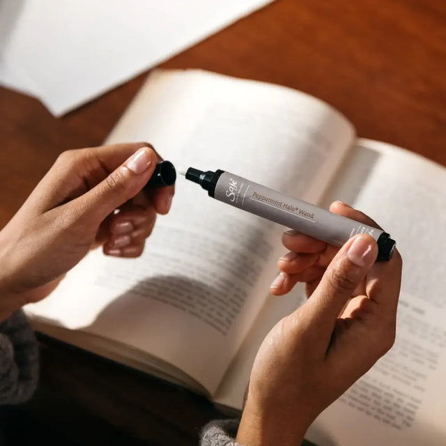 A person pulling the cap off of a peppermint halo wand