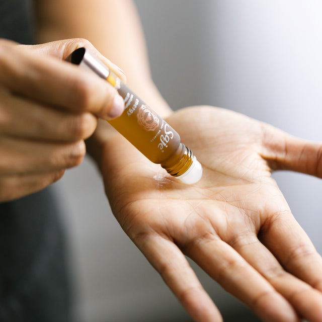 A person applying Energy roll-on to the palm of their hand