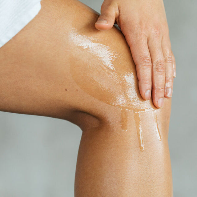 Pain release body oil being rubbed into a person knee cap