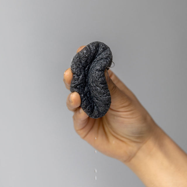 A person holding Konjac Kare bamboo charcoal purifying vegetable fibre sponge 