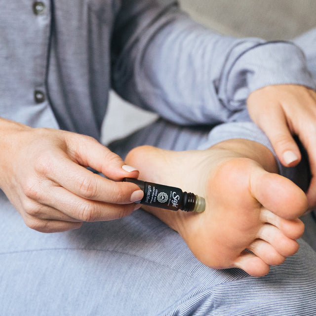 Person rolling sleep well roll-on on the soles of their feet